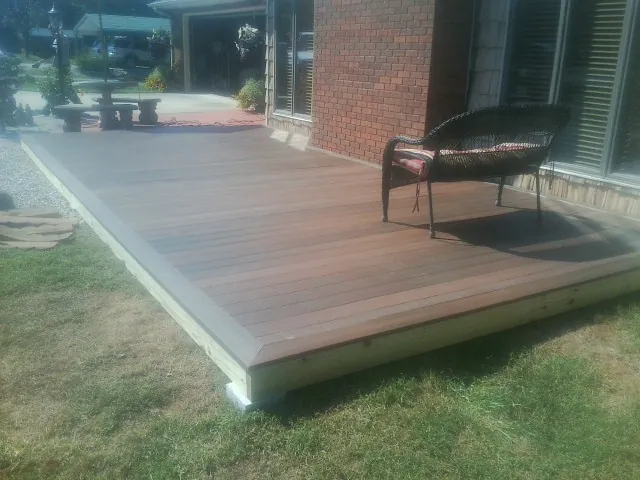 New wood deck and wicker chair beside a brick house in Woodstock