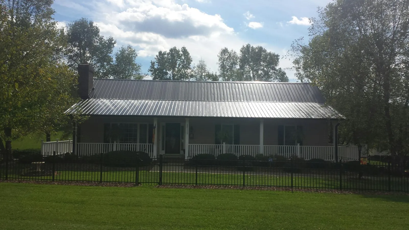 Gray metal roof on a brick ranch with a full width front porch — Gutter Guard Installation work by our crew in Woodstock